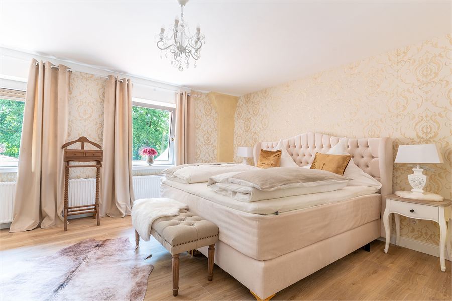 Helles Hotelzimmer mit Kronleuchter und Polsterbett